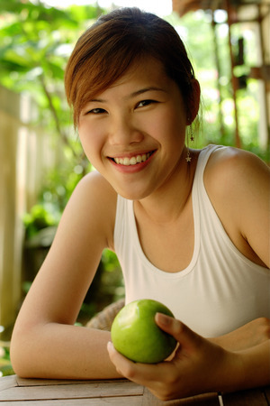 Woman holding an apple, looking at cameraの写真素材