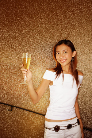 Young woman holding champagne glass, looking at cameraの写真素材