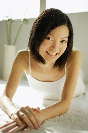 Young woman lying on front, looking at cameraの写真素材