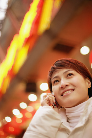 Young woman using mobile phone, looking upの写真素材