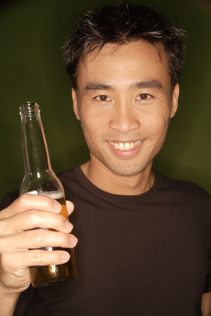 Young man holding beer bottle, portraitの写真素材