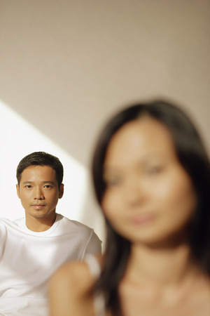 Young man looking at camera, woman in front of himの写真素材