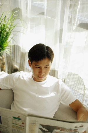 Young man reading newspaperの写真素材