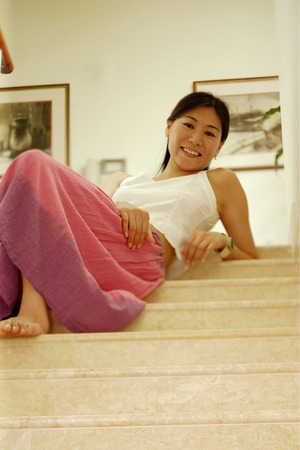Woman sitting on stairs, looking downの写真素材