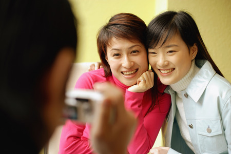 Young man holding camera, two women posing for pictureの写真素材