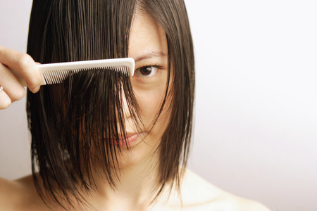Young woman combing her wet hairの写真素材