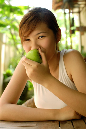Woman eating apple, looking at cameraの写真素材
