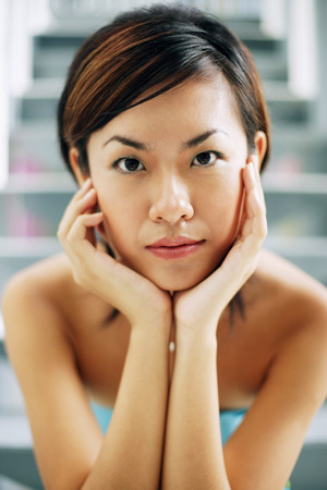 Young woman, looking at camera, hands on faceの写真素材