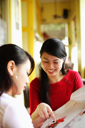 Young women in cafe, looking at newspaperの写真素材