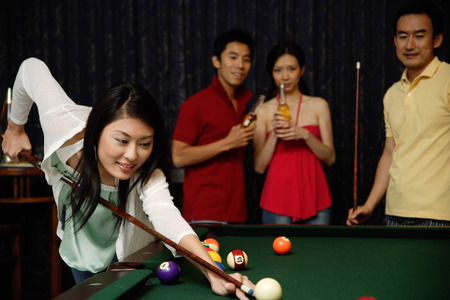 Woman playing snooker, people watchingの写真素材