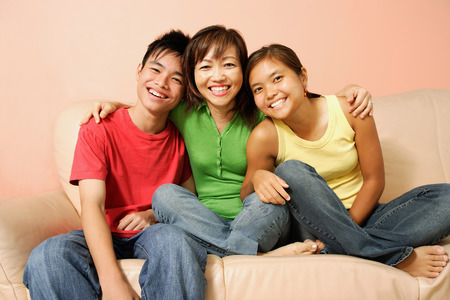 Mother with son and daughter, sitting on sofa, smiling