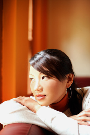 Young woman with arms crossed, head on arms, looking awayの写真素材
