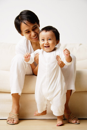 Baby boy standing, mother supporting him