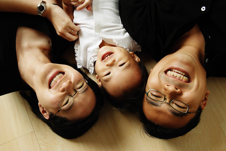 Family with one child lying on floor looking at cameraの写真素材