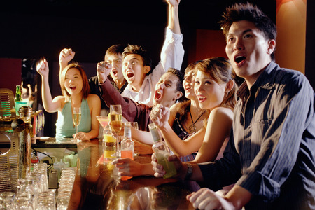 Group of friends sitting at bar, watching somethingの写真素材