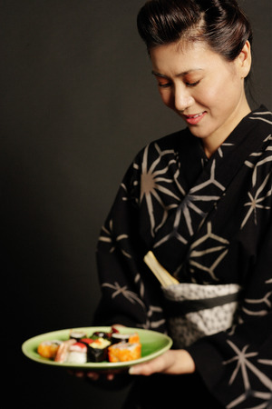 Woman in Japanese costume, holding plate of Japanese foodの写真素材