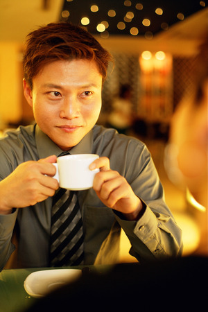 Couple in restaurant, man holding cupの写真素材