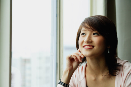 Woman with hand on chin, looking awayの写真素材