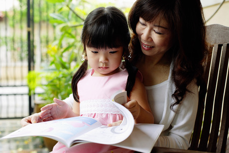 Grandmother and granddaughter looking at bookの写真素材