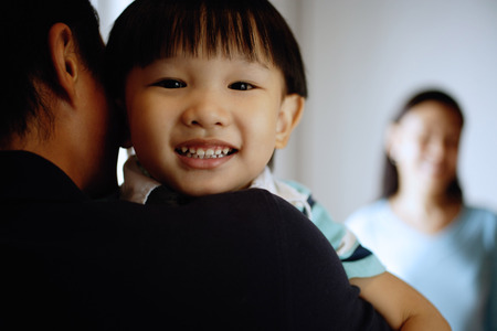 Young boy looking over father's shoulderの写真素材