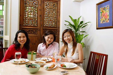 Women sitting at table smiling at camera, portraitの写真素材