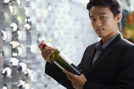 Man in wine cellar, holding bottle of wineの写真素材