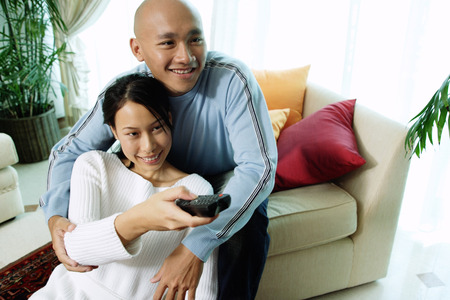 Couple in living room, woman holding remote controlの写真素材