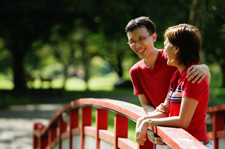 Couple standing on bridge, looking awayの写真素材