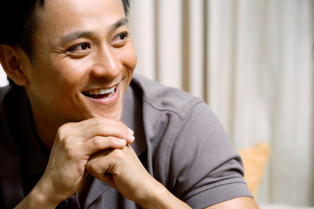 Man looking away, hands clasped, hand on chinの写真素材