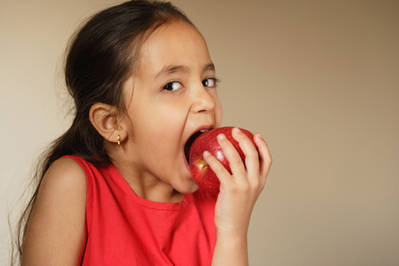 little girl biting into appleの写真素材
