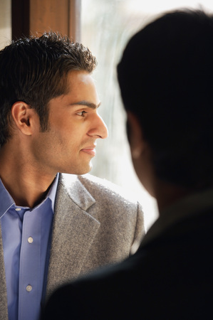 two male colleagues, one looking out window (close up, vertical)の写真素材