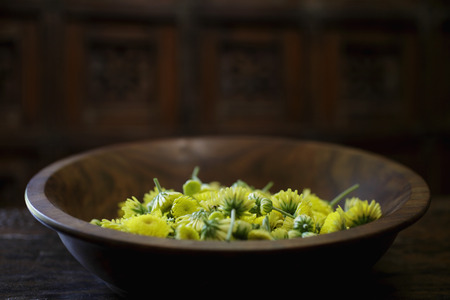 Yellow chrysanthemum flowers in wooden bowlの写真素材