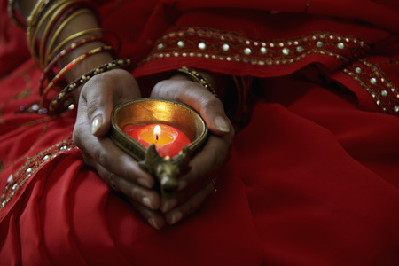 Close up of woman wearing red sari and holding lit candleの写真素材