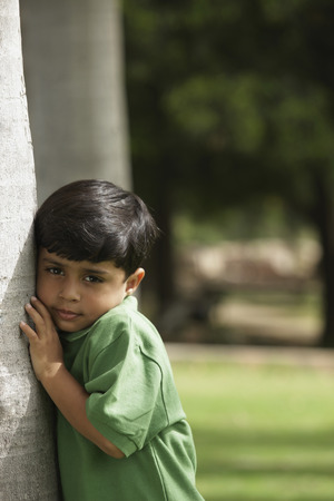 Little boy hugging tree trunkの写真素材