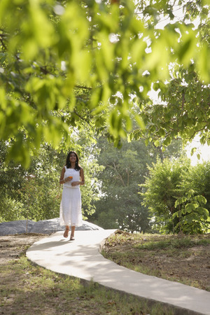 teen girl walking on path through parkの写真素材
