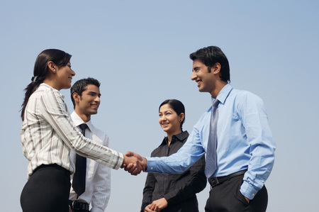 four business colleagues, two shaking handsの写真素材