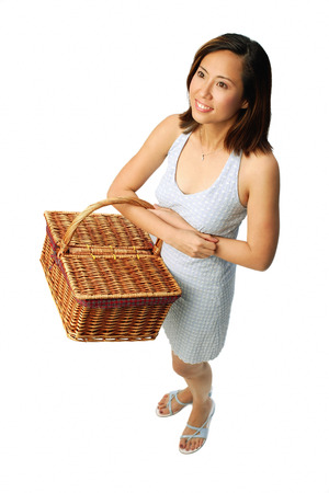 Woman carrying picnic basket, looking awayの写真素材