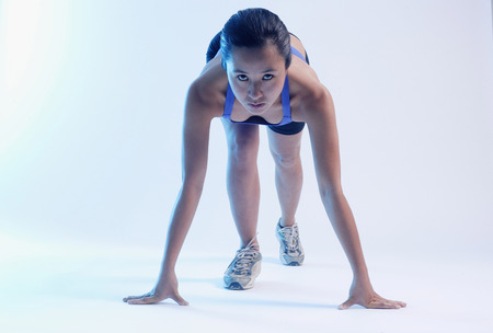 Woman bending over at starting position, looking at cameraの写真素材