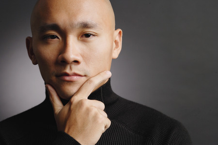 Man with shaved head, hand on chin, portraitの写真素材