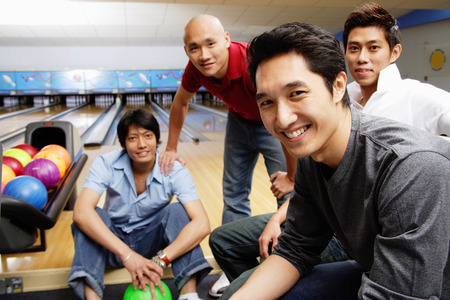 Four men in bowling alley, looking at cameraの写真素材