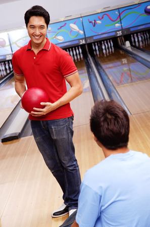 Man holding bowling ball, standing in bowling alleyの写真素材