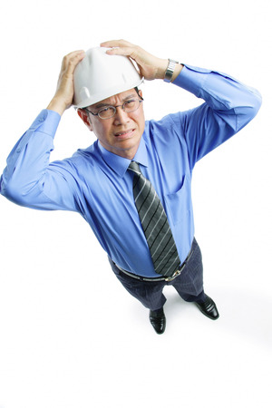 Man wearing hardhat frowning, hands on headの写真素材