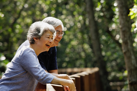 Mature couple leaning on railing, laughing, looking awayの写真素材