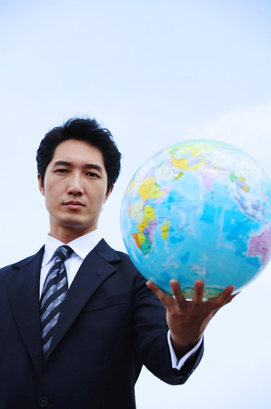Businessman holding globe towards cameraの写真素材