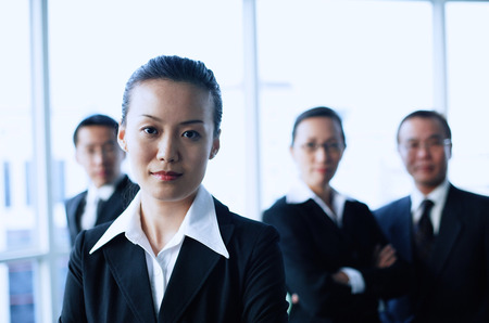 Businesswoman looking at camera, people in the background