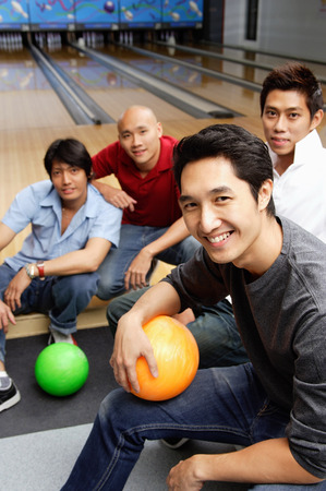 Four men in bowling alley, smiling at cameraの写真素材