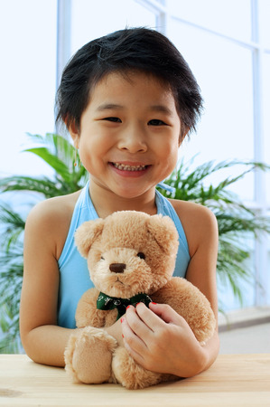 Young girl holding teddy bear, smiling at cameraの写真素材