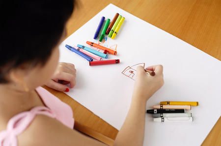 Girl drawing on paper, over the shoulder viewの写真素材