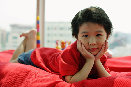 Young girl lying on sofa, looking at camera, hands on faceの写真素材