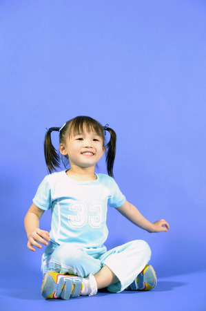 Girl sitting cross-legged, smilingの写真素材